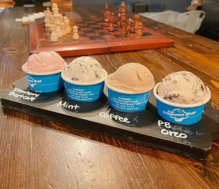 Ice cream flight of four mini cups on a slate board with handwritten flavor labels
