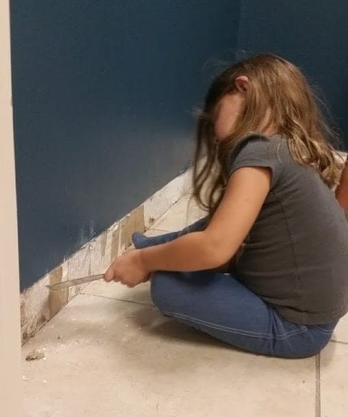 A child helping paint the shop wall trim
