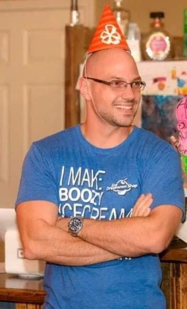 Founder smiling in a party hat and an Ice Dreammm T-shirt, arms crossed