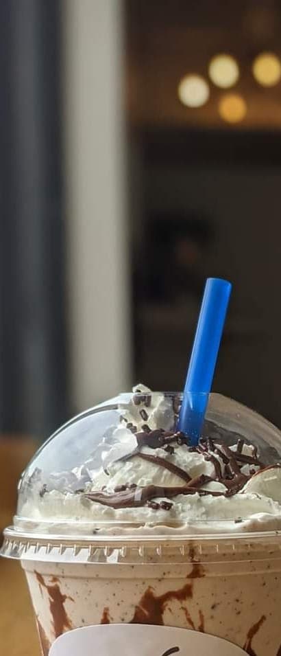 Two handspun milkshakes with whipped cream in shop cups
